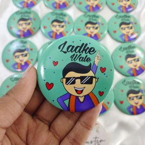 a mint-green LadkeWale Printed Brooches featuring a cartoon man in sunglasses and a traditional outfit with "Ladke Wale" written above him accessory for groom's side members during wedding ceremonies, baraat day, or nikah events