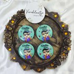 displaying a mint-green brooch with a cartoon figure in sunglasses and traditional outfit, text "Ladke Wale." Several matching brooches are scattered behind Great for baraat day, nikah ceremonies, or as unique wedding favors.
