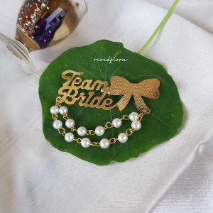 Team Bride brooches with a gold bow and pearls is a stylish accessory for bridal parties and wedding attire
