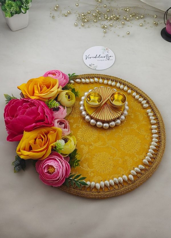 Roli Kumkum Pooja Platter wedding and nikah ceremonies. The platter features a bright yellow fabric base with intricate floral patterns, bordered by white pearls. Adorned with vibrant artificial flowers in shades of pink, yellow, and peach, the platter includes two small golden cups placed on a circular arrangement of pearls, perfect for holding roli and kumkum or rings