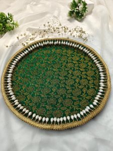 Beautifully decorated mehndi platter with a green and gold floral pattern and pearl border, featuring a mehndi cone and colorful stick making it a stunning addition to any wedding ritual