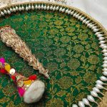 A green and gold floral mehndi ceremony platter bordered with pearls, featuring a traditional mehndi cone and a colorful decorative stick where it can be used to present henna cones and other ceremonial items