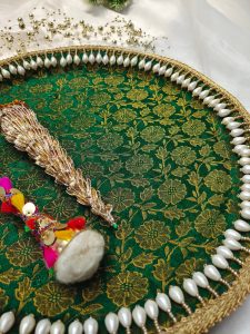A green and gold floral mehndi ceremony platter bordered with pearls, featuring a traditional mehndi cone and a colorful decorative stick where it can be used to present henna cones and other ceremonial items