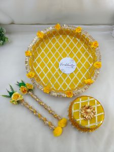 Bright yellow and gold steel platter for Haldi and Henna ceremonies, featuring a lattice design with golden trims and adorned with yellow flowers and a pearl-accented round steel box This decorative platter is a charming way to celebrate your joyous moments and makes a delightful gift for any bride-to-be