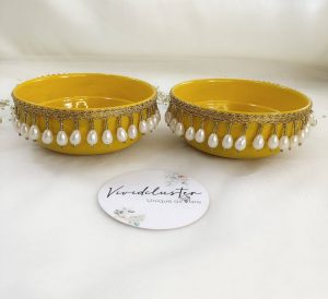 Charming yellow and gold steel bowl with a lattice design, golden trims, and yellow flower accents, featuring a round box for Haldi and Henna ceremonies The centerpiece round steel haldi box, with its pearl accents, is ideal for holding Haldi, Henna, or other special items wedding favor