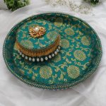 Green and gold bangle chura ceremony platter with intricate floral motifs and pearl tassel border serve as a decorative piece for various wedding functions
