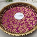 Decorative bangle ceremony platter with vibrant pink and gold floral design, embellished with intricate golden lace and pearl accents. Perfect for wedding functions, adding elegance to bangle ceremonies
