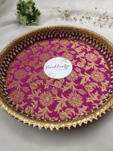 Decorative bangle ceremony platter with vibrant pink and gold floral design, embellished with intricate golden lace and pearl accents. Perfect for wedding functions, adding elegance to bangle ceremonies