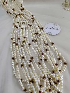 Wedding accessory featuring multi-layered pearls with gold and maroon details. Perfect for baaratis, this decorative flower milni mala also makes a thoughtful Punjabi milni gift