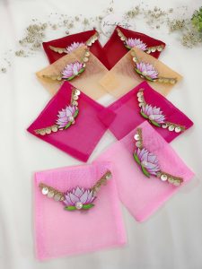 Set of lotus net shagun envelopes in various shades, decorated with golden lace and lotus motifs, perfect for wedding favor giveaways