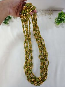 Indian wedding milni featuring a handcrafted green beaded mala necklace with latest gold accents for your haldi mehendi ceremony to look different in functions.