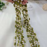 Elachi designed Welcome Milni Mala Moti Haar with green and gold beads and pearls, laid out on a white fabric, ideal for Nikah ceremonies and wedding traditions