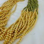 Elachi designed Welcome Milni Mala Moti Haar with green and gold beads and pearls, laid out on a white fabric, ideal for Nikah ceremonies and wedding traditions