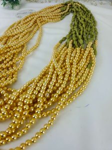 Elachi designed Welcome Milni Mala Moti Haar with green and gold beads and pearls, laid out on a white fabric, ideal for Nikah ceremonies and wedding traditions