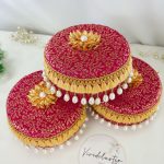 red color laddu boxes with intricate gold patterns and pearl decorations or shagun laddus, barati gifts, and bridesmaids' presents