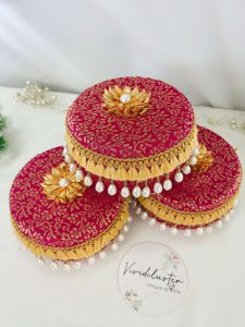 red color laddu boxes with intricate gold patterns and pearl decorations or shagun laddus, barati gifts, and bridesmaids' presents