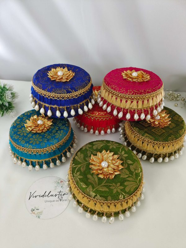 A set of four beautifully decorated round laddu boxes in vibrant blue fabric with intricate golden floral patterns Each box is adorned with a golden floral motif topped with a pearl its a gift laddu box for Barati, Bridesmaids, Shagun Laddu Boxes