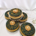 Beautiful green laddu boxes with gold floral motifs and pearl decorations traditional sweets to present to guests, making them a functional and beautiful addition to the ceremony
