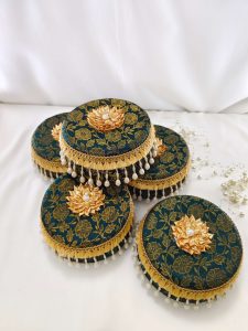 Beautiful green laddu boxes with gold floral motifs and pearl decorations traditional sweets to present to guests, making them a functional and beautiful addition to the ceremony