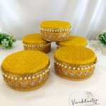 Stylish wedding laddu boxes with yellow and gold detailing and pearl accents in teal, green, yellow, and white, featuring a durable stainless steel interior