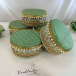 Decorative laddu shagun boxes in bright colors with elegant gold embroidery and pearls, showcasing their use for wedding and engagement ceremonies return gift
