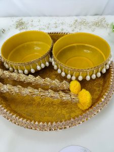 beautiful yellow Haldi ceremony platter set with intricate lace and pearl decorations have two beautiful yellow bowls, intricately trimmed with pearls and golden lace, and adorned with charming yellow flowers for wedding haldi celebration