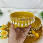 two elegant yellow bowls decorated with delicate pearl trim and complemented by intricate golden lace for holding the turmeric paste used in the Haldi ritual a perfect blend of tradition