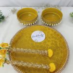 Haldi ceremony platter with yellow bowls, decorated with pearls and golden lace, perfect for weddings, and adorned with charming yellow flowers for wedding haldi celebration