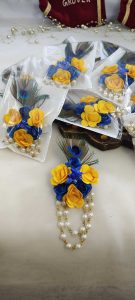 Decorative brooch with a peacock feather, blue flowers and peral chain ideal for wedding favors and coat accessories.