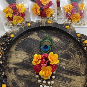 Wedding-themed brooch showcasing a colorful peacock feather, pink flower, pearls, and golden decoration, perfect for guests