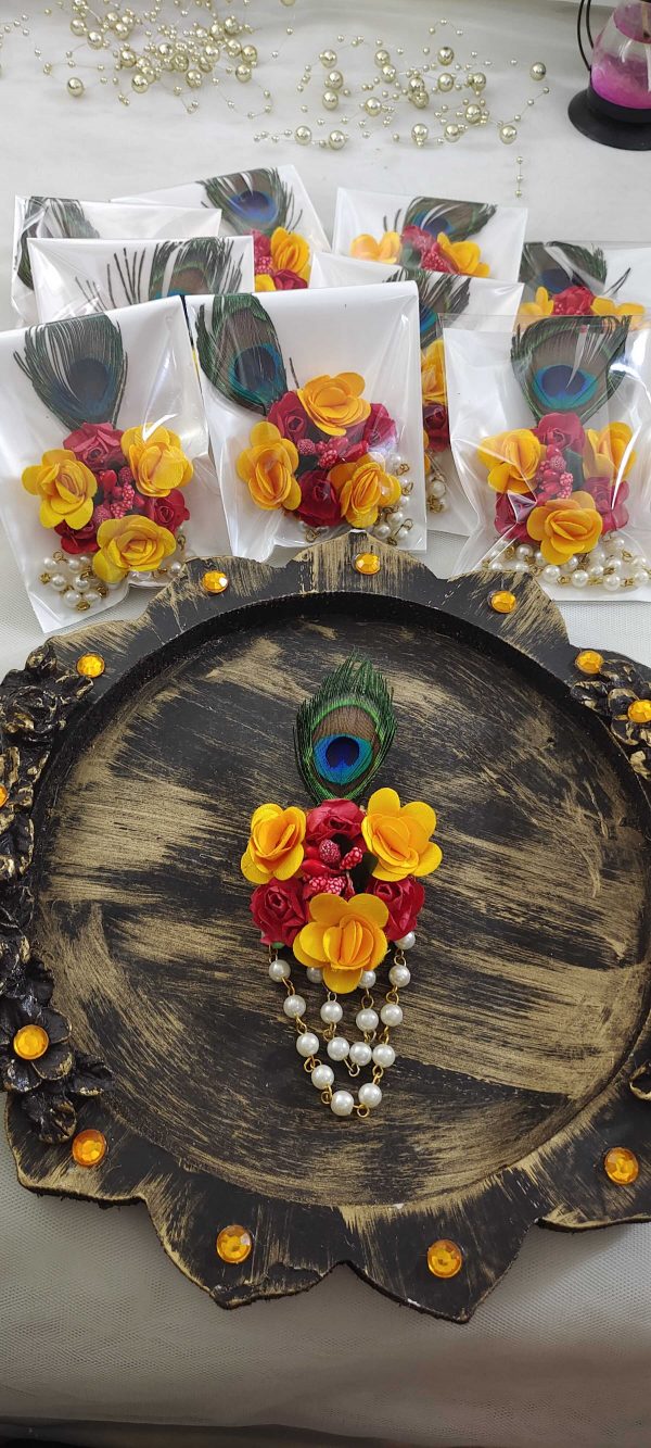 Wedding-themed brooch showcasing a colorful peacock feather, pink flower, pearls, and golden decoration, perfect for guests