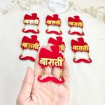 A collection of acrylic Baarati brooches in red and gold, perfect for wedding favors and coat accessories for the groom’s side at Nikah ceremonies
