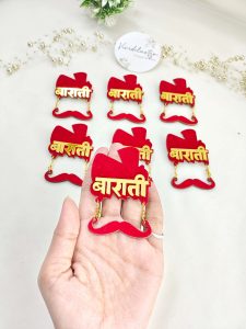 A collection of acrylic Baarati brooches in red and gold, perfect for wedding favors and coat accessories for the groom’s side at Nikah ceremonies