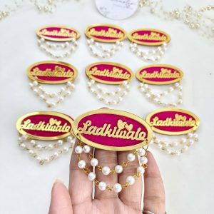 Ladkiwale badge featuring pearl and red bead decorations. Ideal for nikah ceremonies, wedding favors, baarati brooches, and bridal accessories