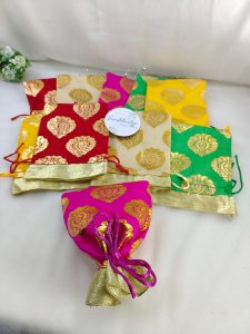 A vibrant collection of traditional tissue wedding potlis in various colors, designed with golden motifs, perfect for wedding favors.