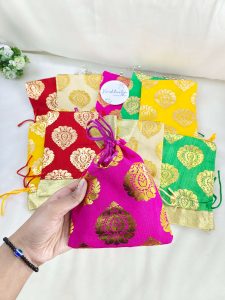 issue potlis in red, yellow, green, and cream, adorned with gold patterns, suitable for wedding and anniversary gifts