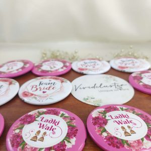 a pink and white ladkiwale brooch featuring the text Ladki Wale brooch with a floral print accessory for bride's side members during wedding ceremonies, baraat day, or nikah events
