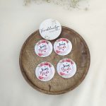 A round, pink, white brooch with the words bride side and a delicate flower design for the bride's side. Perfect for baraat day, nikah ceremonies, or as a unique wedding favor