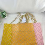three colorful Lehariya printed bags, each with a distinct zigzag pattern in yellow, orange, and pink. Ideal for use as wedding favor Nikah ceremonies and other wedding events