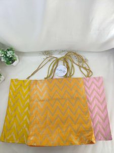 three colorful Lehariya printed bags, each with a distinct zigzag pattern in yellow, orange, and pink. Ideal for use as wedding favor Nikah ceremonies and other wedding events