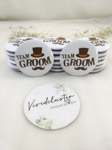 Multiple white round badges with "TEAM GROOM" printed in bold brown letters, accompanied by a stylish brown top hat and mustache graphic Ideal for wedding favors, especially for the groom's party.