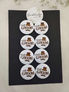 several white "TEAM GROOM" pins with a brown top hat and mustache design, Suitable for groomsmen brooches at weddings and nikah ceremonies.