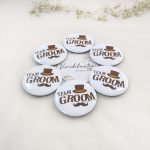 White circular pins with "TEAM GROOM" in bold brown font, accented by a brown top hat and mustache, Ideal for nikah ceremonies and wedding party accessories