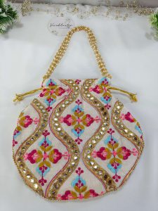 a beautifully crafted potli bag with intricate embroidery featuring colorful flowers and shimmering gold accents erfect for use as a wedding favor, nikah ceremony gift, or bridesmaid's present.