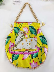 Drawstring potli bag showcasing a tranquil cow motif amidst a colorful floral backdrop, ideal for wedding favors and bridesmaids gifts