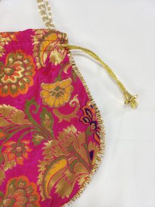 pink potli bag decorated with gold embroidery and finished with a gold drawstring, suitable for bridal use, wedding accessories, and festive gifting