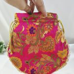 A vibrant pink potli bag featuring detailed gold floral embroidery and a golden drawstring, perfect for use as a wedding favor, bridesmaid gift, or nikah ceremony accessory.