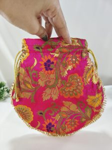 A vibrant pink potli bag featuring detailed gold floral embroidery and a golden drawstring, perfect for use as a wedding favor, bridesmaid gift, or nikah ceremony accessory.