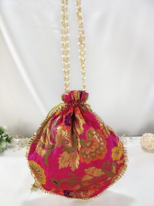 A traditional Indian potli bag in pink with gold floral patterns, complemented by a gold drawstring closure, perfect for wedding giveaways, nikah ceremonies, and shagun gifting