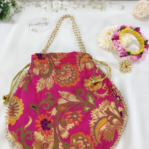 A beautifully handcrafted pink potli bag featuring detailed gold embroidery and a matching gold drawstring, ideal for use as a bridal accessory, wedding favor, or engagement ceremony pouch